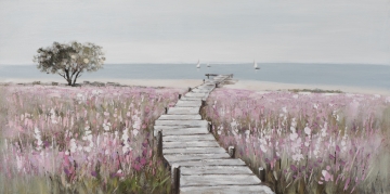 Een houten looppad kronkelt door een veld vol paarse en roze bloemen, met een rustige zee en zeilboten op de achtergrond.