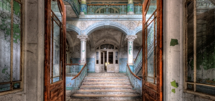 Decrepite trappenhuis met verwoeste muren in blauwtinten, houten deuren en vervagende decoratieve elementen. Decrepite trappenhuis met verwoeste muren in blauwtinten, houten deuren en vervagende decoratieve elementen.