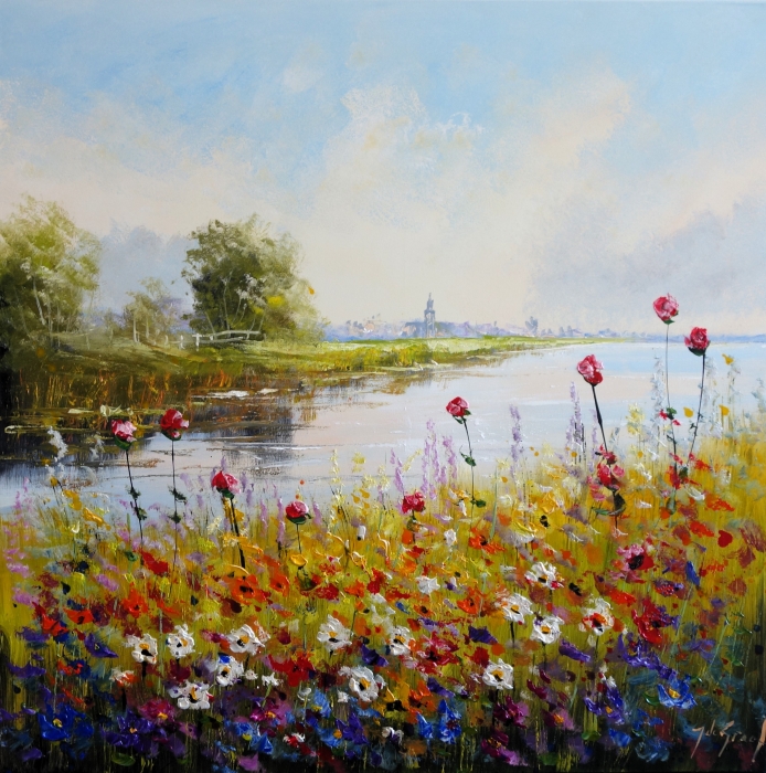 Kleurrijke bloeiende bloemen in levendige tinten bij een kalme rivier, met een stralende lucht en op de achtergrond een stad.