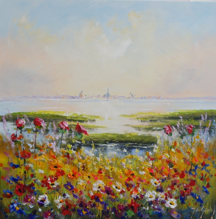 Kleurrijke bloemen in rood, geel en blauw bloeien voor een serene waterpartij onder een heldere hemel.